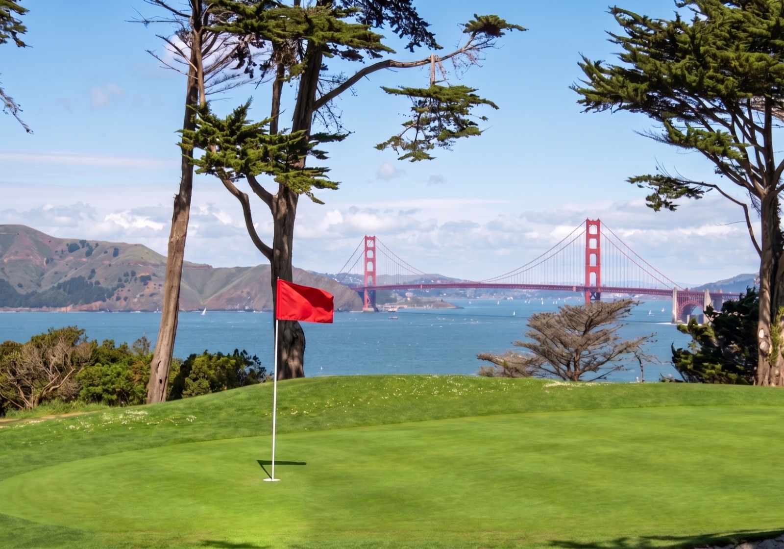 A golf green with a red flag overlooking the Golden Gate Bridge